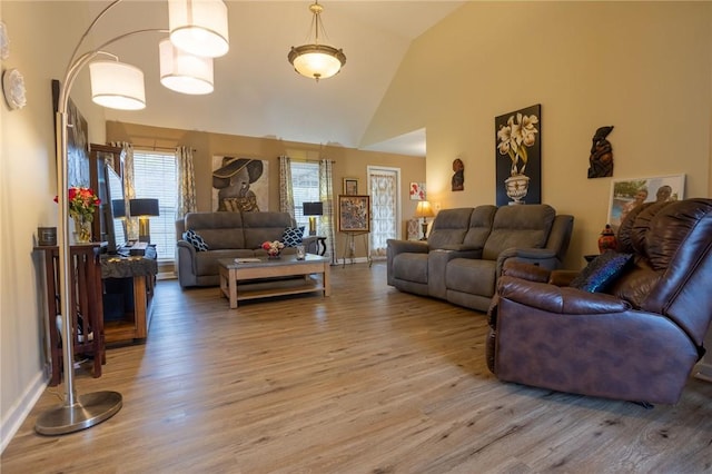living area with baseboards, light wood-type flooring, and high vaulted ceiling