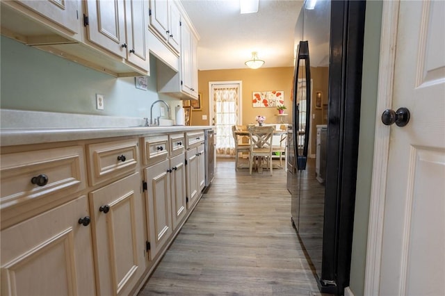 kitchen with light countertops, a sink, light wood-style floors, and freestanding refrigerator