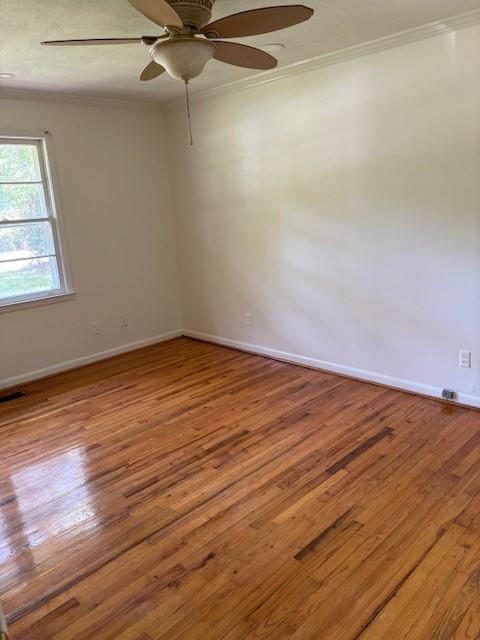 empty room featuring ceiling fan, wood-type flooring, and ornamental molding