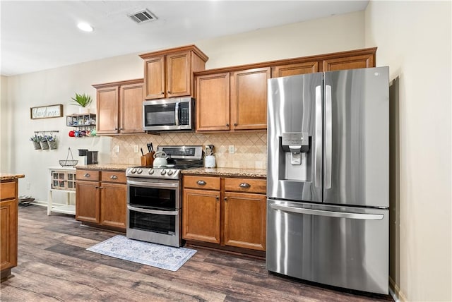 172 Solamere Ln, Auburn, AL 36832 - kitchen with stainless steel appliances, brown cabinets, dark wood finished floors, light stone counters, and recessed lighting