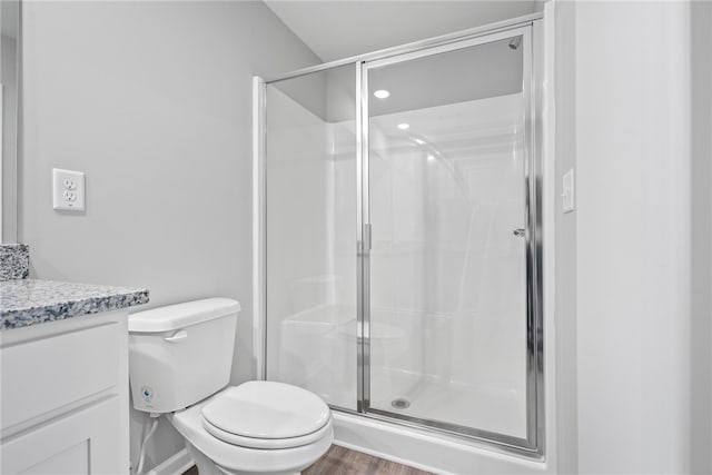 bathroom with hardwood / wood-style flooring, toilet, vanity, and walk in shower