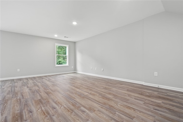 empty room with light wood-type flooring and lofted ceiling