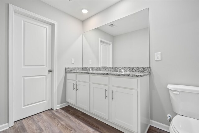 bathroom with hardwood / wood-style floors, vanity, and toilet