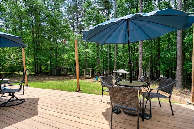 1249 County Road 446, Five Points, AL 36855 - wooden deck with outdoor dining area, a storage shed, and view of wooded area