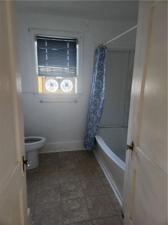 bathroom with toilet and shower / bathtub combination with curtain