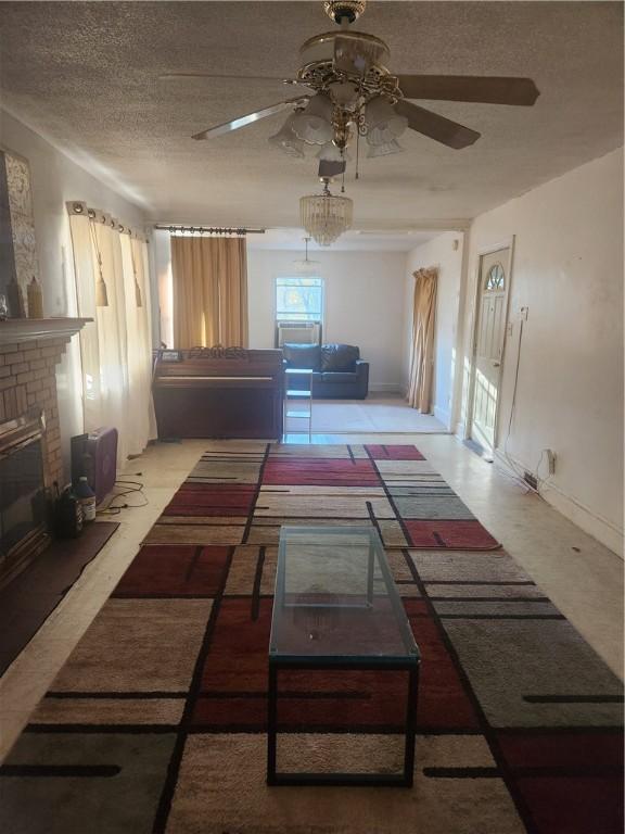 living room with ceiling fan, a textured ceiling, and a brick fireplace