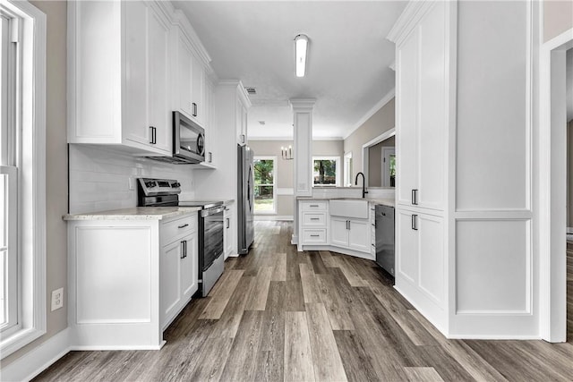 1661 S Camden Ct, Auburn, AL 36830 - kitchen featuring appliances with stainless steel finishes, wood finished floors, white cabinetry, crown molding, and backsplash
