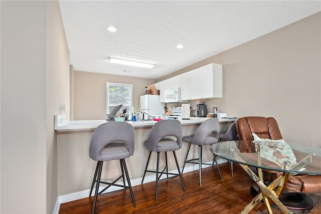 1477 N Donahue Dr Unit 1708, Auburn, AL 36830 - kitchen with white appliances, a breakfast bar, a peninsula, white cabinetry, and recessed lighting