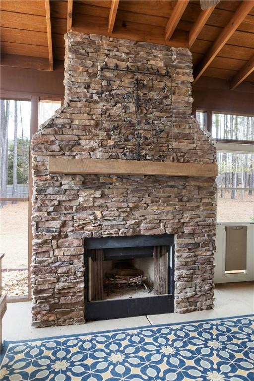 interior details with beam ceiling, an outdoor fireplace, and wood ceiling