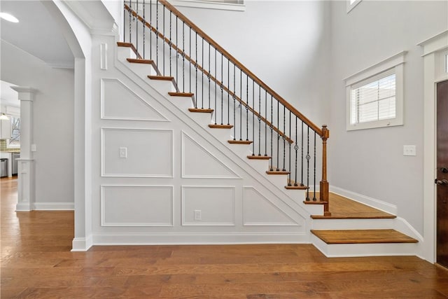 stairs featuring hardwood / wood-style flooring and decorative columns