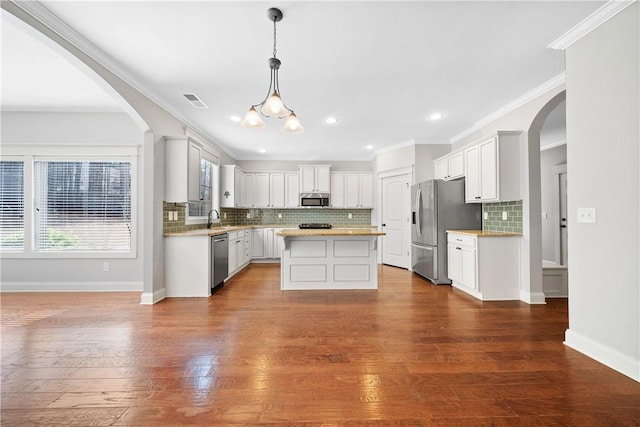 kitchen with white cabinetry, a center island, hanging light fixtures, appliances with stainless steel finishes, and hardwood / wood-style floors