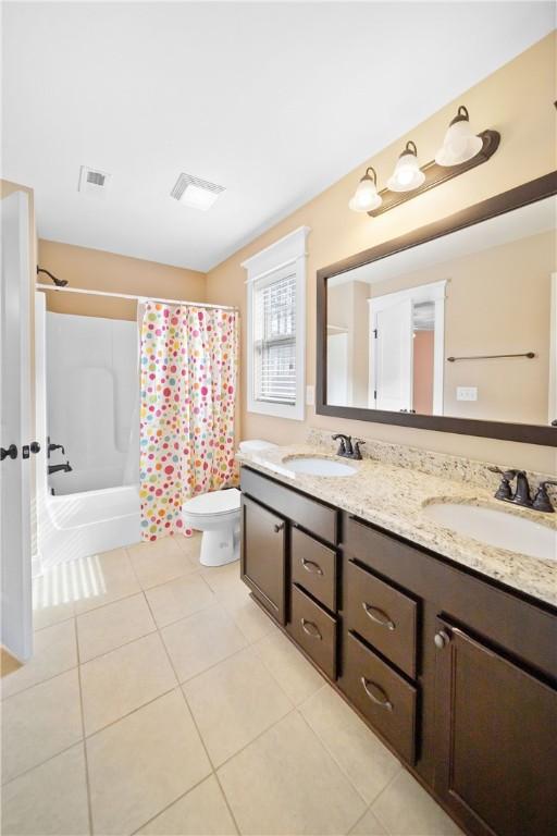 full bathroom with shower / tub combo with curtain, tile patterned floors, toilet, and vanity