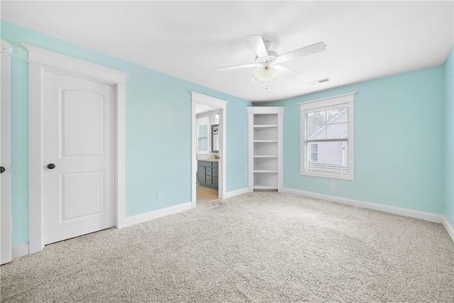 unfurnished bedroom with ceiling fan, ensuite bathroom, and carpet flooring