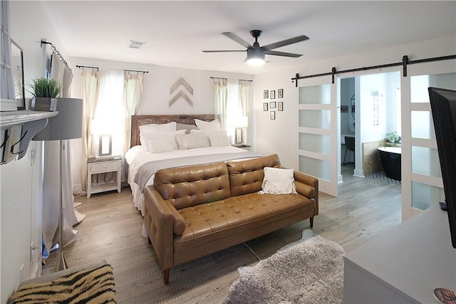 3897 Moores Mill Rd, Auburn, AL 36830 - bedroom with a barn door, multiple windows, light wood finished floors, and ceiling fan