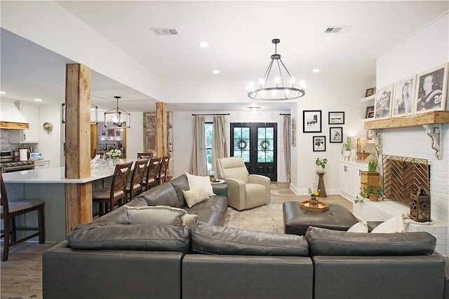 3897 Moores Mill Rd, Auburn, AL 36830 - living room with light wood-style flooring, a chandelier, recessed lighting, french doors, and a brick fireplace