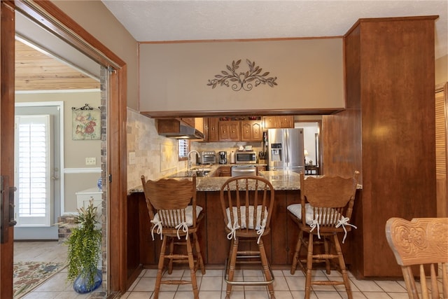 2071 County Road 63, Tuskegee, AL 36083 - kitchen with appliances with stainless steel finishes, wall chimney range hood, light tile patterned floors, tasteful backsplash, and a peninsula