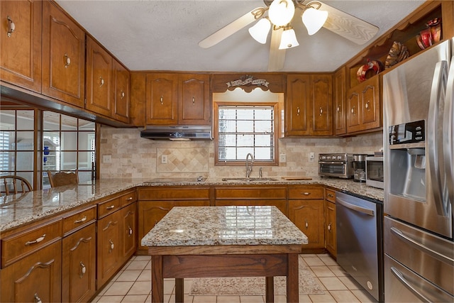 2071 County Road 63, Tuskegee, AL 36083 - kitchen with stainless steel appliances, a sink, brown cabinetry, under cabinet range hood, and decorative backsplash