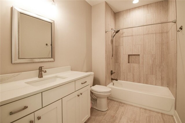 full bathroom featuring tiled shower / bath, vanity, and toilet