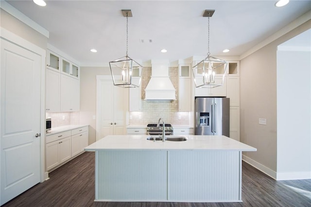 kitchen with premium range hood, appliances with stainless steel finishes, pendant lighting, and an island with sink