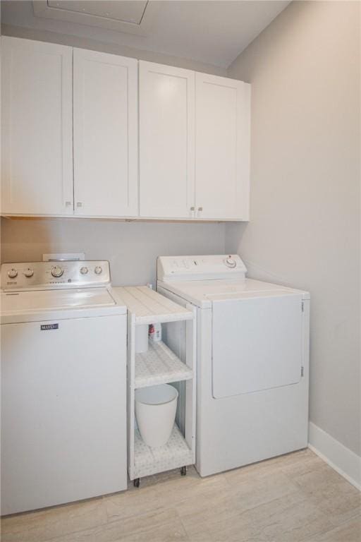 clothes washing area with cabinets, separate washer and dryer, and light wood-type flooring