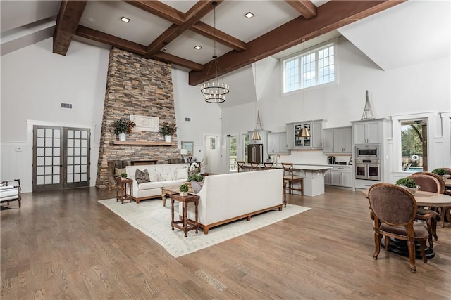 living room featuring beam ceiling, hardwood / wood-style flooring, french doors, and an inviting chandelier