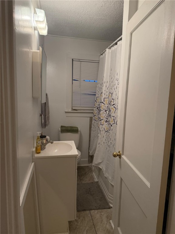 full bathroom with shower / bath combo, vanity, a textured ceiling, tile patterned flooring, and toilet