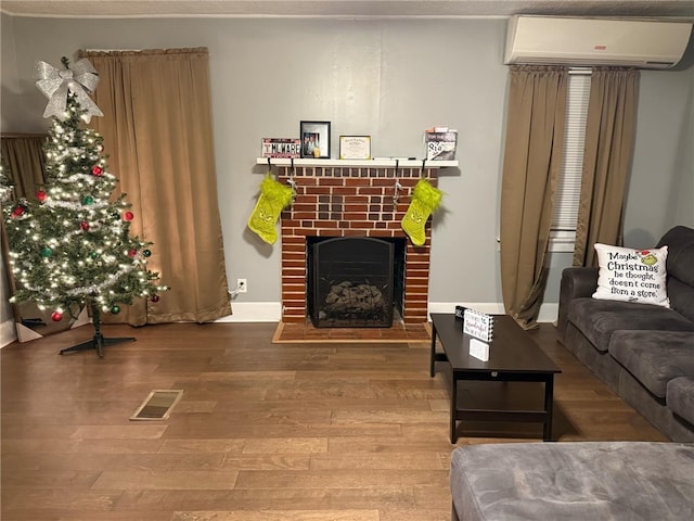 living room with a wall unit AC, a fireplace, and hardwood / wood-style floors