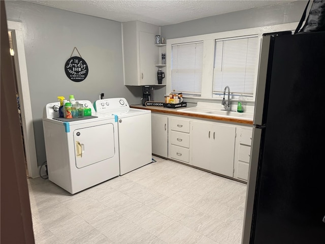 laundry room featuring cabinets, sink, washing machine and dryer, and a textured ceiling