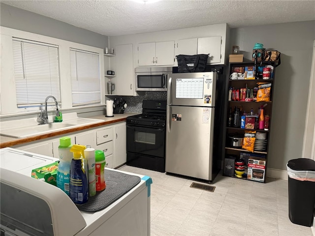 kitchen featuring backsplash, sink, a textured ceiling, white cabinetry, and stainless steel appliances