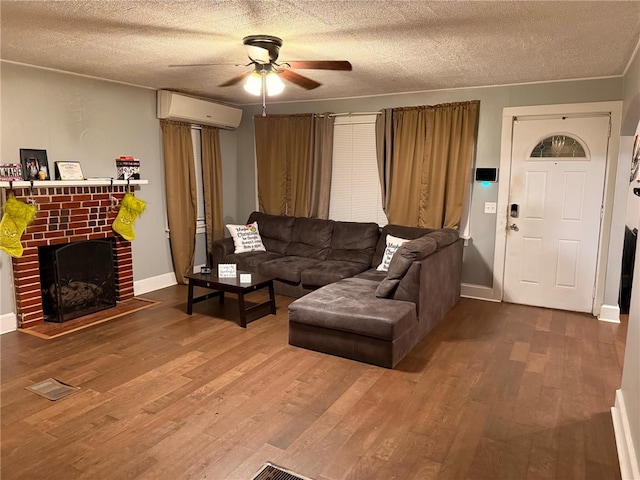 living room featuring a wall mounted air conditioner, ceiling fan, a fireplace, a textured ceiling, and wood-type flooring