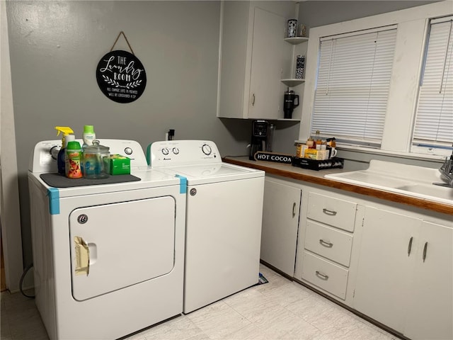 clothes washing area with cabinets, sink, and washing machine and clothes dryer