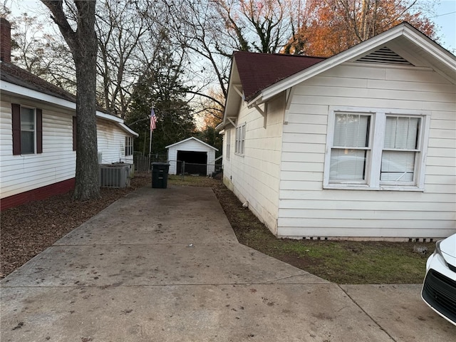 view of property exterior featuring cooling unit, an outdoor structure, and a garage