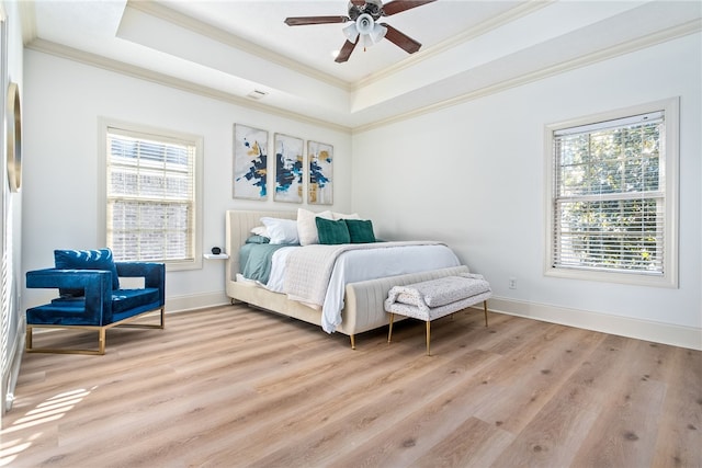 bedroom featuring ceiling fan, light hardwood / wood-style flooring, multiple windows, and a raised ceiling