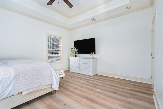 bedroom with ceiling fan, light hardwood / wood-style flooring, ornamental molding, and a raised ceiling