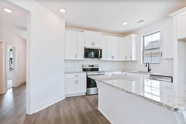 7 Crossing Ct E, Valley, AL 36854 - kitchen with appliances with stainless steel finishes, wood finished floors, white cabinets, backsplash, and a kitchen island