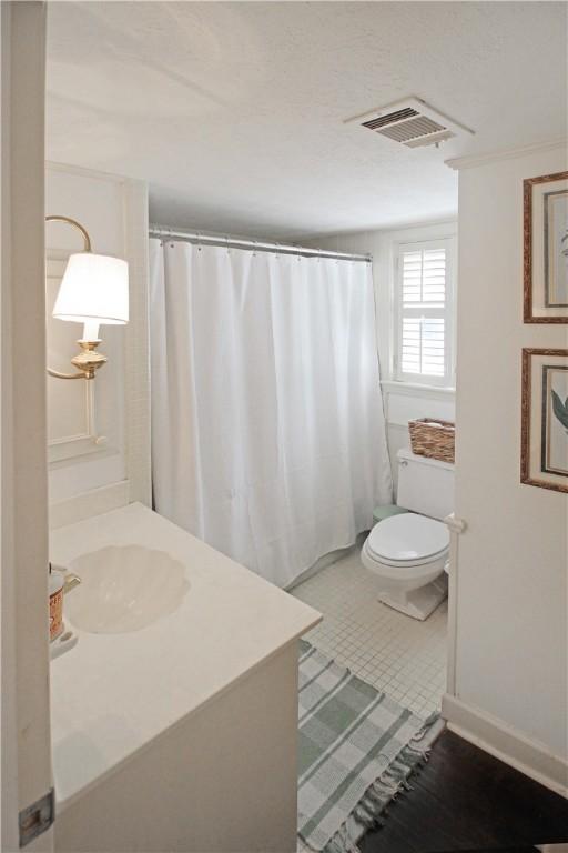 bathroom featuring toilet, ornamental molding, and sink