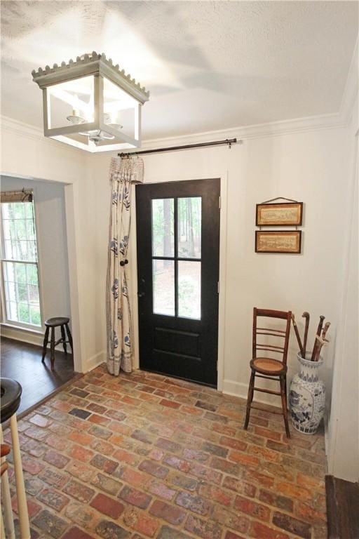 foyer entrance with ornamental molding and a textured ceiling