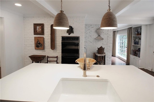 kitchen with ornamental molding, black double oven, hanging light fixtures, and dark wood-type flooring