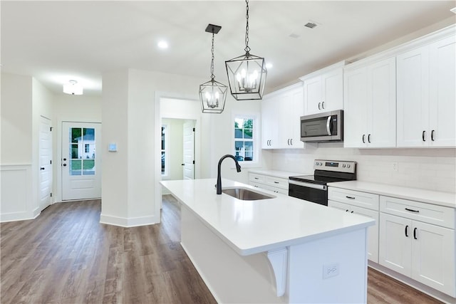 109 Hunters Way, Opelika, AL 36801 - kitchen featuring appliances with stainless steel finishes, a kitchen island with sink, wood finished floors, backsplash, and light countertops