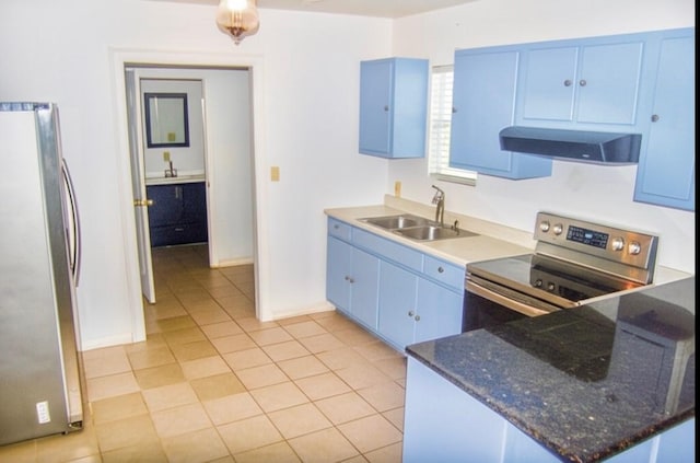 kitchen featuring wall chimney range hood, a peninsula, blue cabinetry, appliances with stainless steel finishes, and a sink