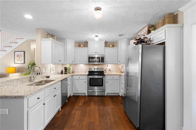 304 Marthas Ct, Opelika, AL 36801 - kitchen with stainless steel appliances, a sink, white cabinets, dark wood finished floors, and light stone countertops