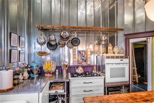 kitchen featuring dark stone counters, oven, and stainless steel gas cooktop