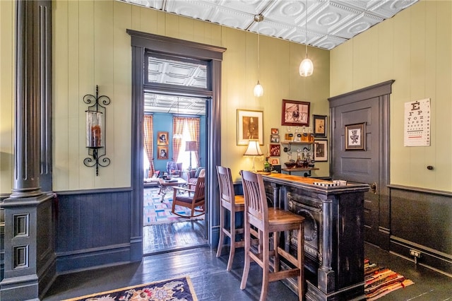 bar with dark wood-style floors, a dry bar, an ornate ceiling, and decorative light fixtures