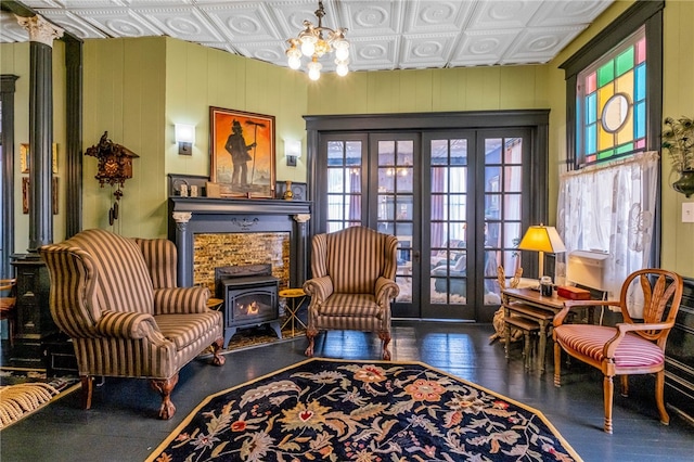 living area featuring an ornate ceiling, french doors, a wood stove, wood finished floors, and a chandelier