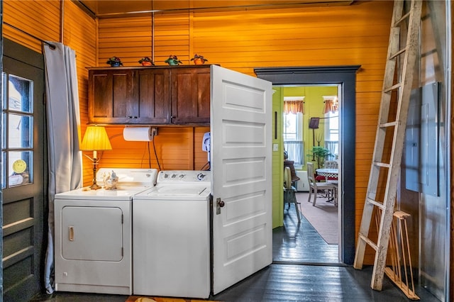 washroom with cabinet space, wooden walls, dark wood-type flooring, and independent washer and dryer