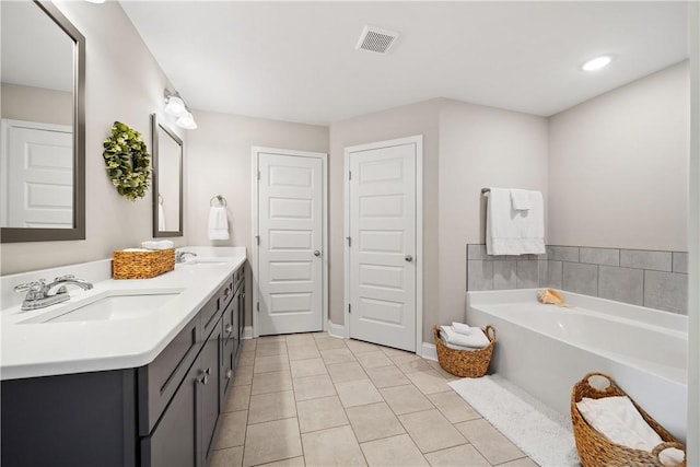 bathroom with tile patterned floors, a garden tub, double vanity, and baseboards