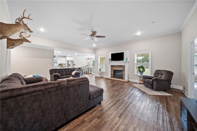 living area with a ceiling fan, crown molding, dark wood-style floors, a stone fireplace, and recessed lighting