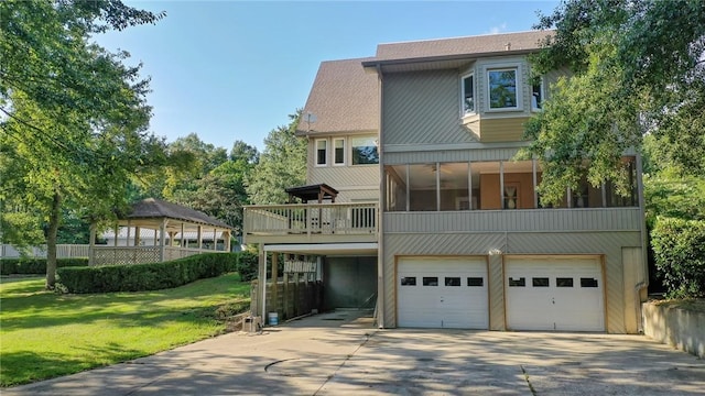 rear view of property with a lawn, a sunroom, a gazebo, and a garage