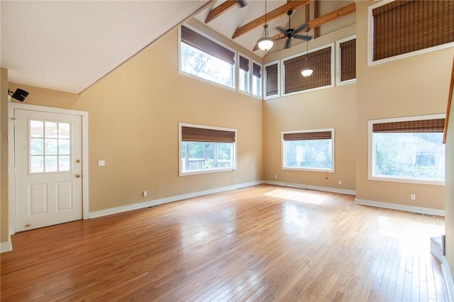 unfurnished living room featuring ceiling fan, plenty of natural light, high vaulted ceiling, and light hardwood / wood-style floors