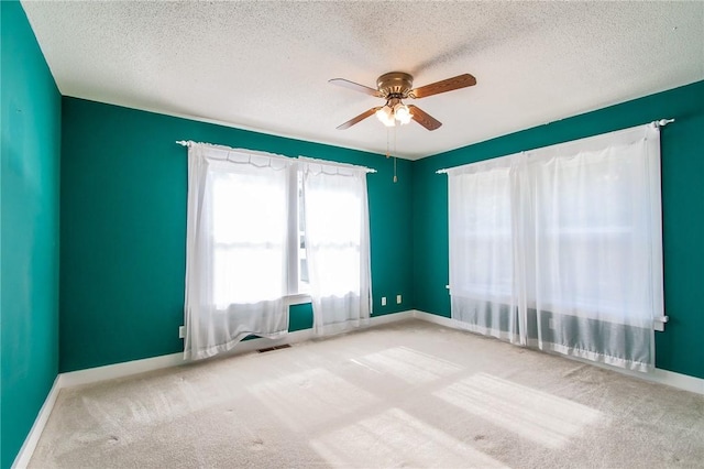 carpeted spare room with ceiling fan and a textured ceiling